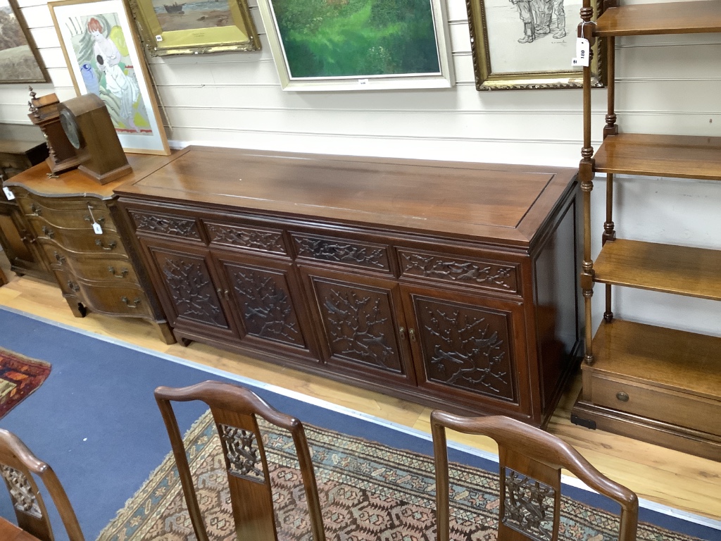 A 20th century Chinese carved hardwood dining room suite comprising sideboard fitted with four drawers above four carved panelled cupboard doors, shelved interior, raised on bracket base, length 183cm, depth 48cm height